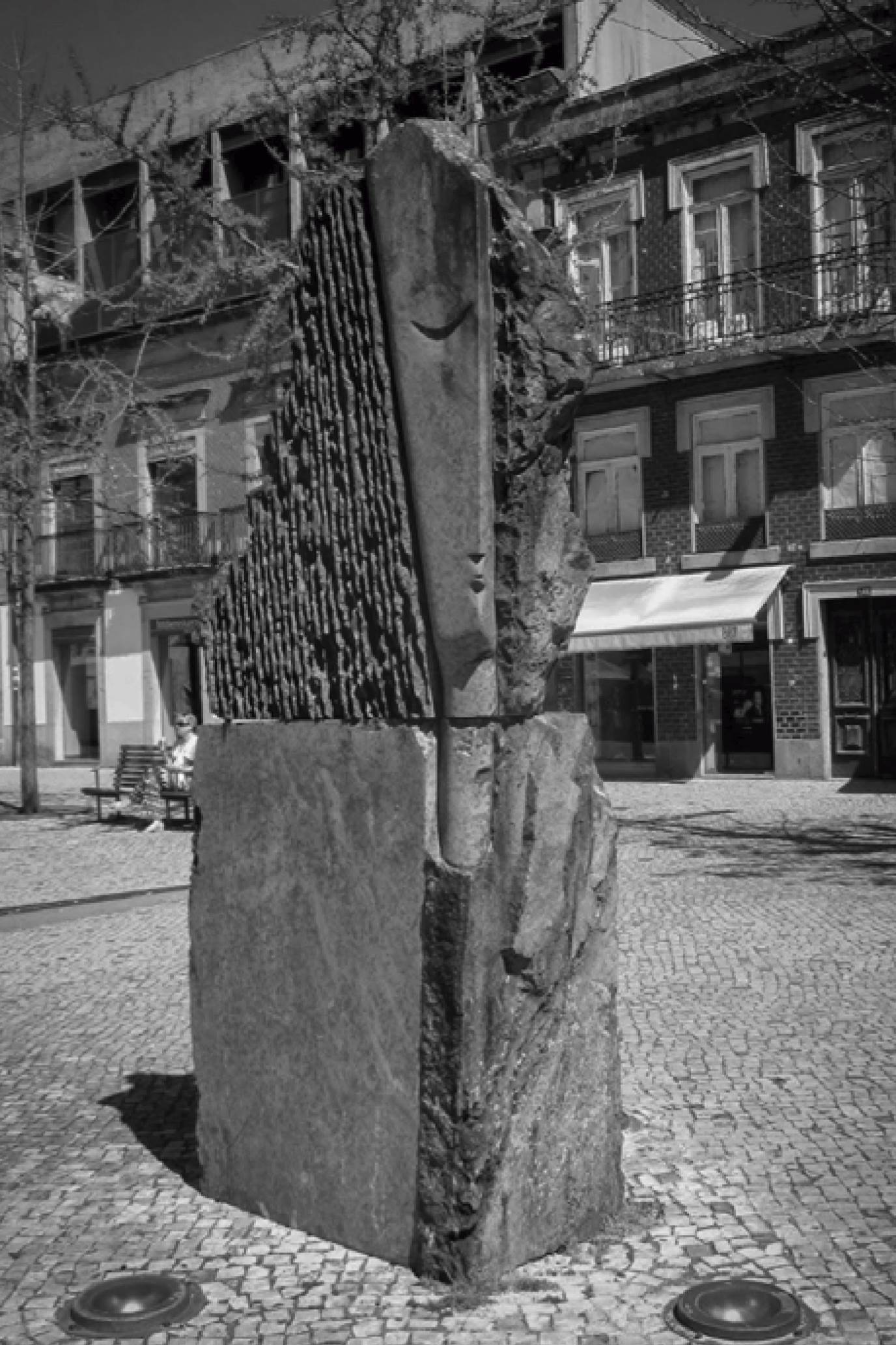 The two sculptural elements, which make up a set, are characterised by four stone blocks superimposed two by two and arranged vertically, suggesting two animal forms, abstract, in confrontation.  The work has the language that characterises the artist, with the grooves contrasting with the rusticity of the stone. 
The work was originally placed in Conde de Agrolongo Square, at the intersection of Capelistas Street and Doutor Justino Cruz Street, but has since been removed and is awaiting a new location.